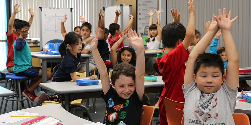 smiling students with hands up