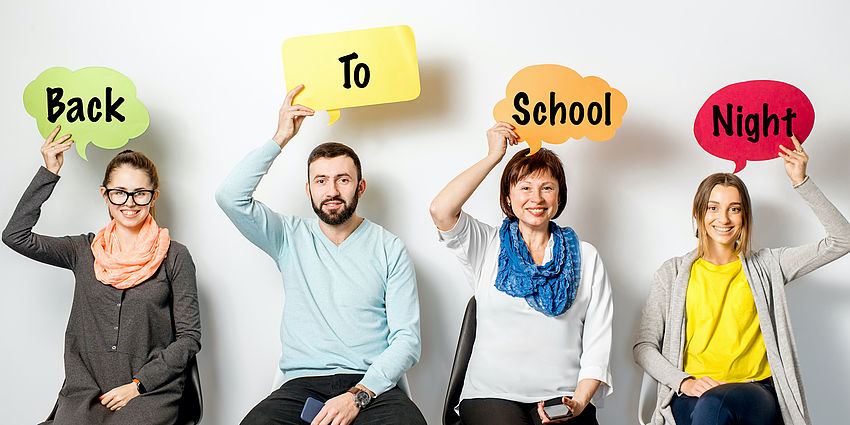 Four adults holding speech bubbles over their heads which say Back to School Night