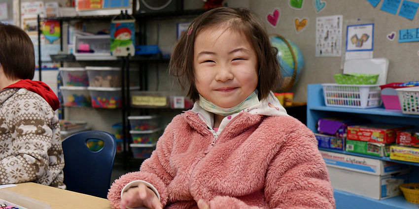 little girl sitting a desk smiling