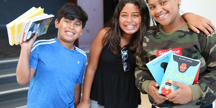 3 smiling students with books