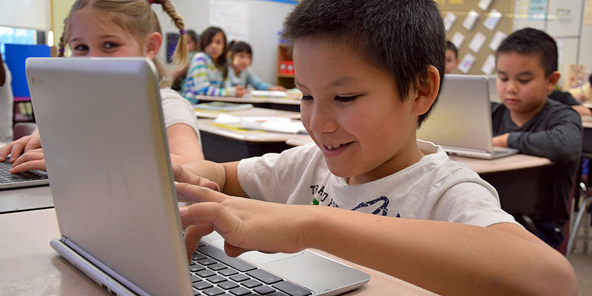 boy looking at laptop keyboard smiling