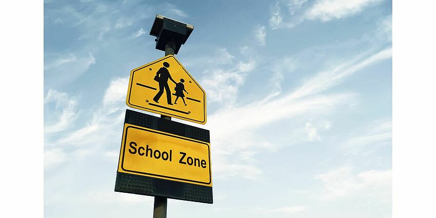Picture of a yellow school zone crossing sign 