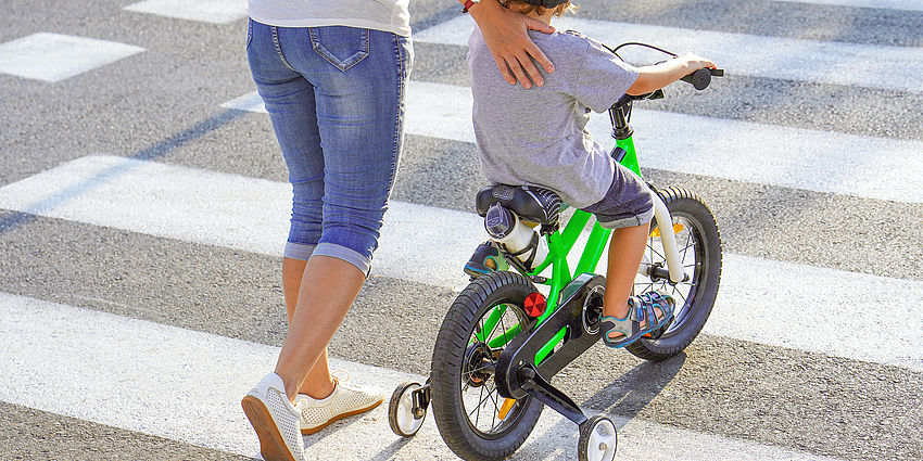 child on bike in crosswalk with adult