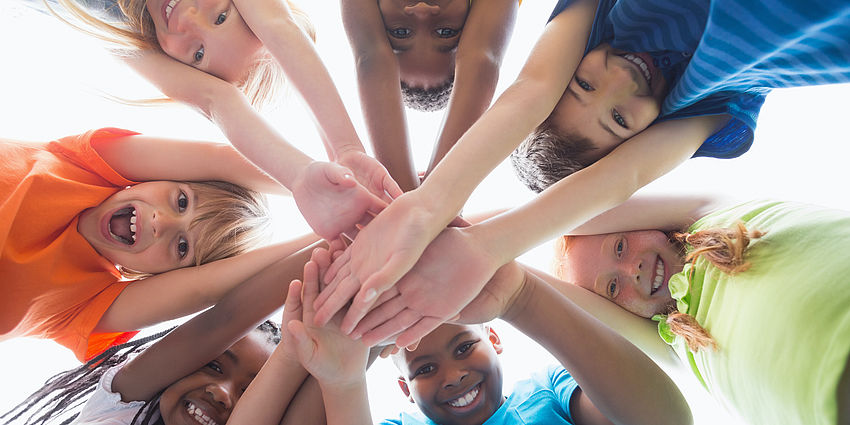 group of students looking down with hands linked together