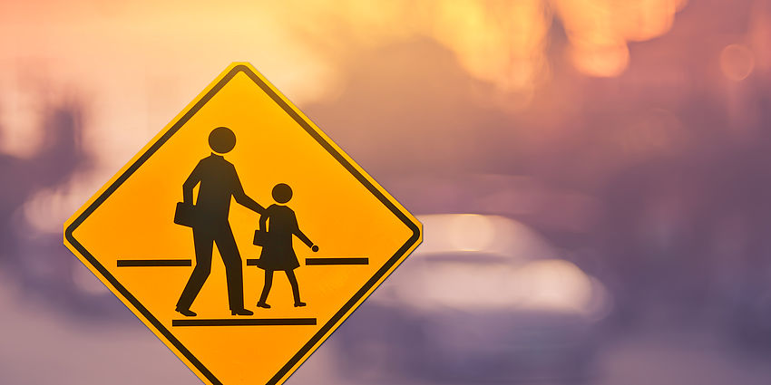 Crossing guard sign with a silhouette of a parent and student