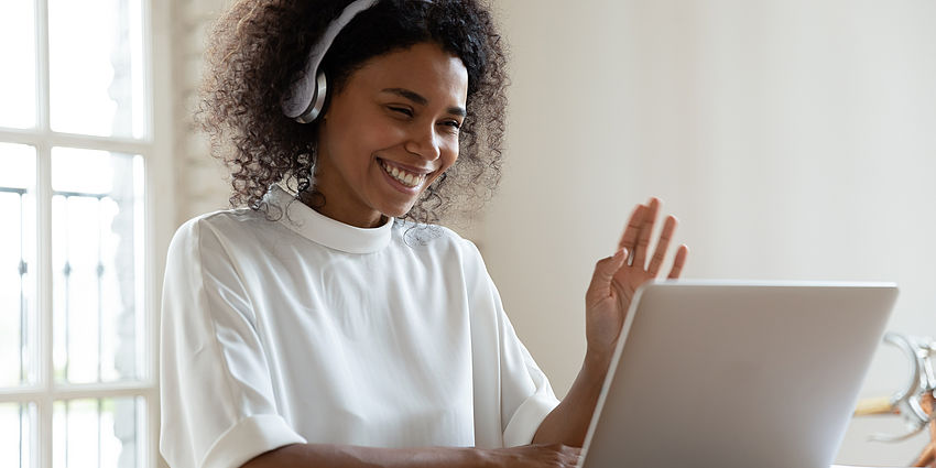 woman teacher waves to students on laptop