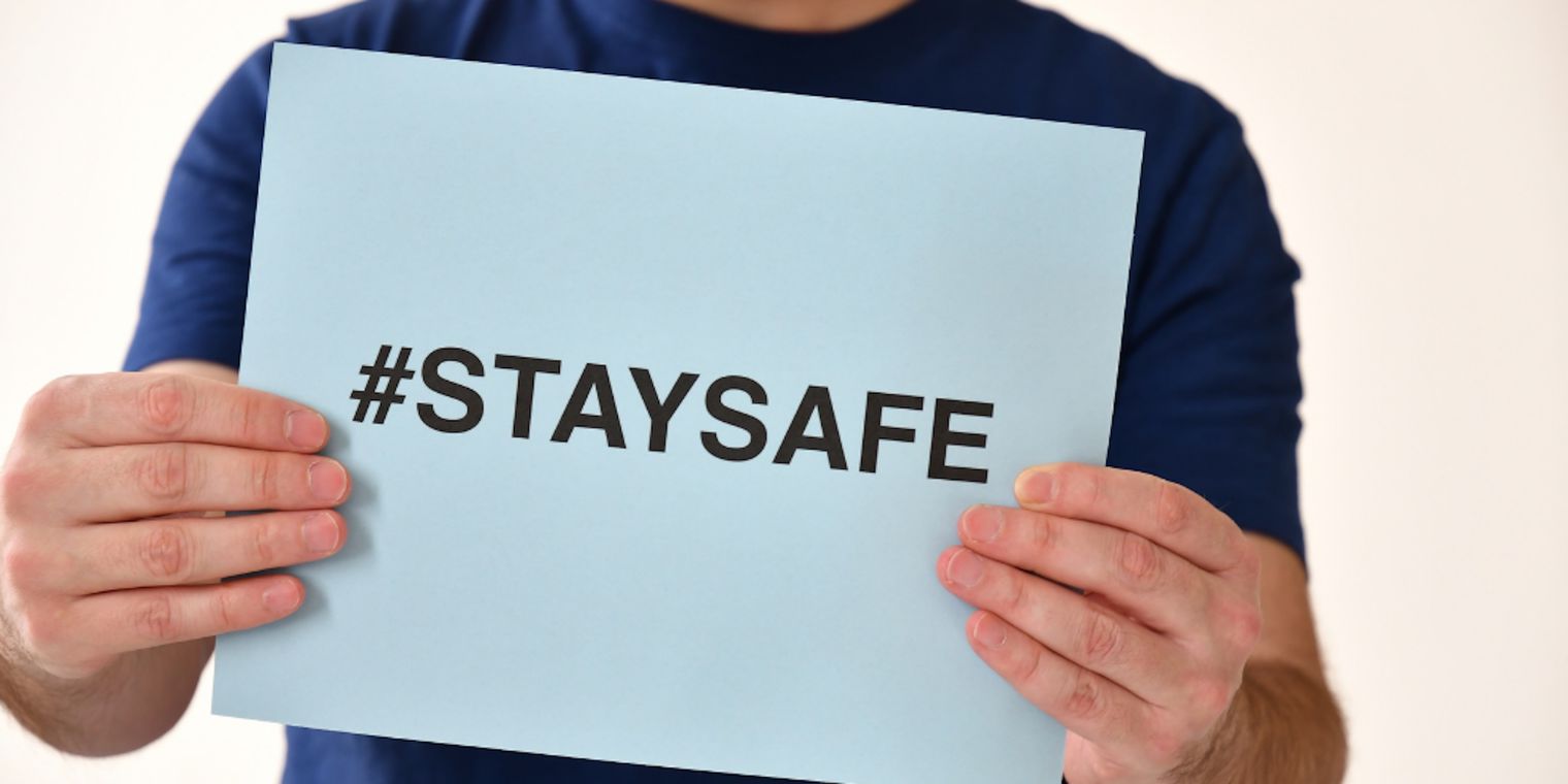 Male holding a sign on blue paper #StaySafe